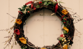 natural autumn wreath with leaves, berries, and knitted leaves on a white front door